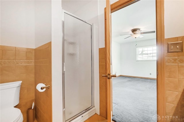 bathroom featuring toilet, ceiling fan, and a shower with shower door