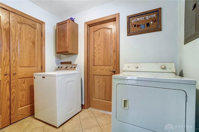 laundry area featuring washer and clothes dryer, light tile patterned floors, and cabinets