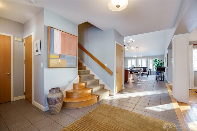 staircase featuring tile patterned flooring and an inviting chandelier