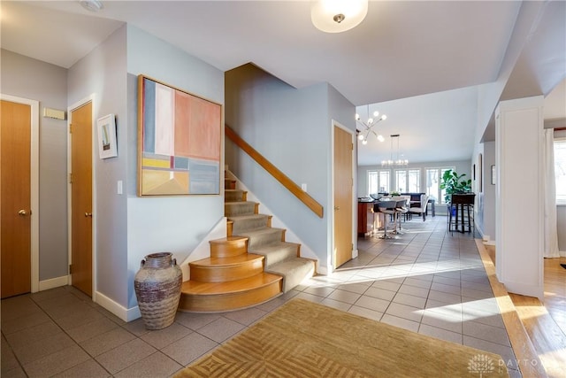 stairway with an inviting chandelier and tile patterned floors