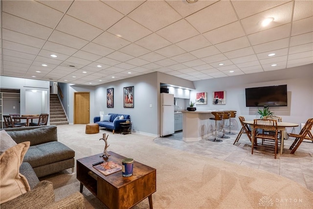 carpeted living room with a paneled ceiling and bar