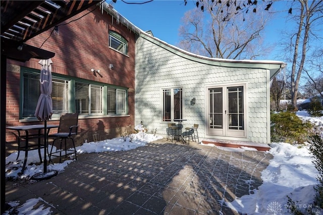 snow covered back of property featuring a patio