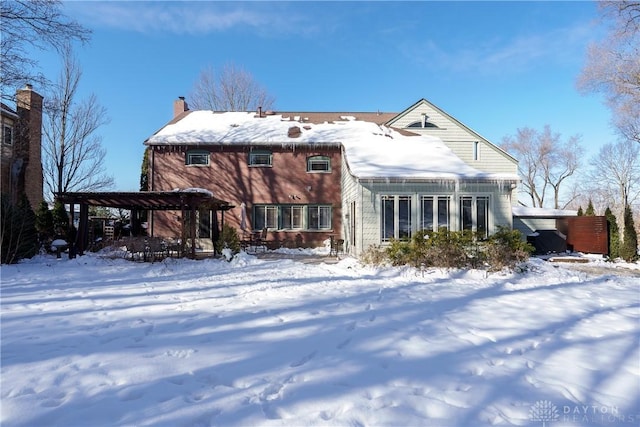 snow covered back of property featuring a pergola