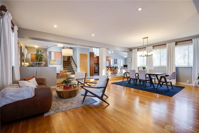 living room featuring light hardwood / wood-style flooring, an inviting chandelier, and decorative columns