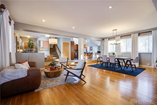 living room featuring light hardwood / wood-style floors, decorative columns, and a notable chandelier