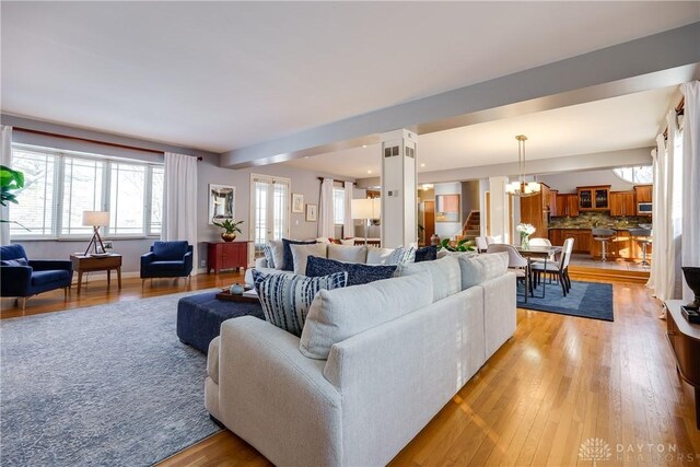 living room featuring a notable chandelier, light hardwood / wood-style floors, and decorative columns