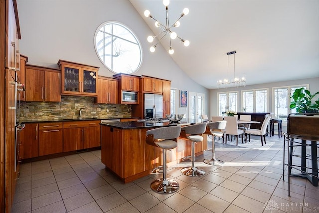 kitchen with built in appliances, light tile patterned floors, a center island, and a chandelier