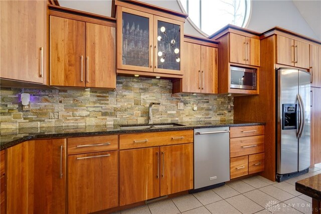 kitchen with sink, dark stone countertops, tasteful backsplash, and appliances with stainless steel finishes