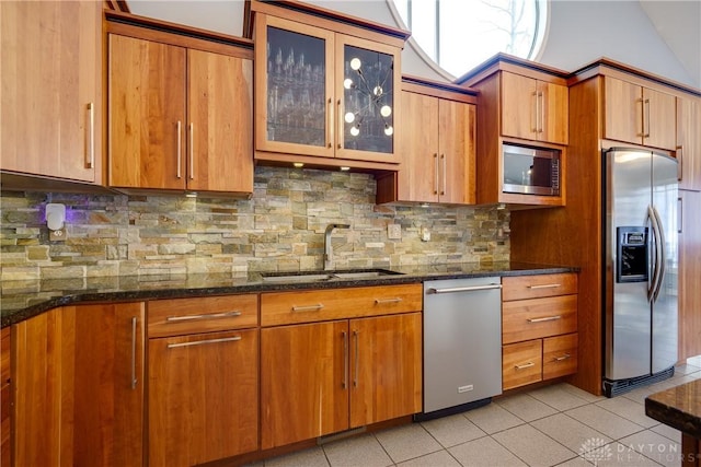 kitchen featuring sink, tasteful backsplash, light tile patterned floors, appliances with stainless steel finishes, and dark stone counters