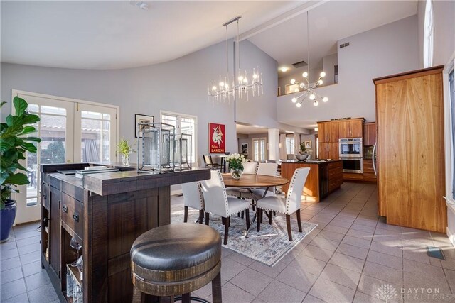 kitchen with a chandelier, hanging light fixtures, a kitchen island, high vaulted ceiling, and tile patterned floors