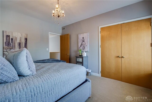 bedroom featuring a closet, a notable chandelier, and carpet floors