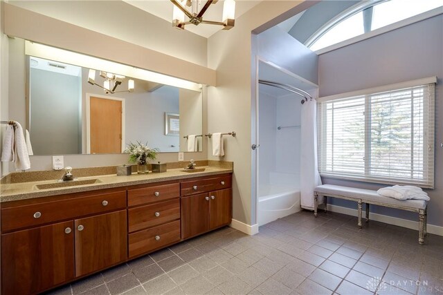 bathroom with tile patterned flooring, an inviting chandelier, a wealth of natural light, and vanity