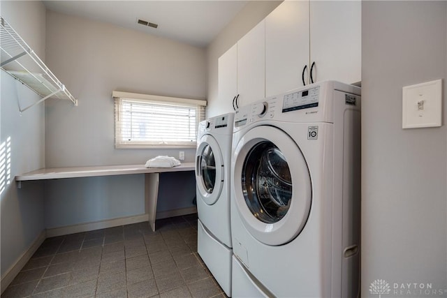 washroom featuring cabinets, separate washer and dryer, and dark tile patterned flooring