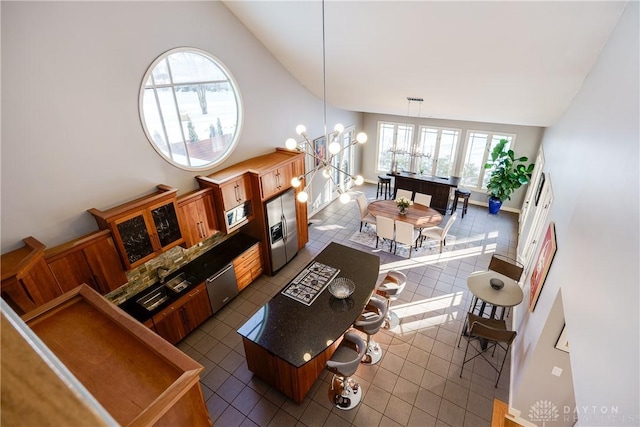 living room featuring dark tile patterned flooring, high vaulted ceiling, and a chandelier