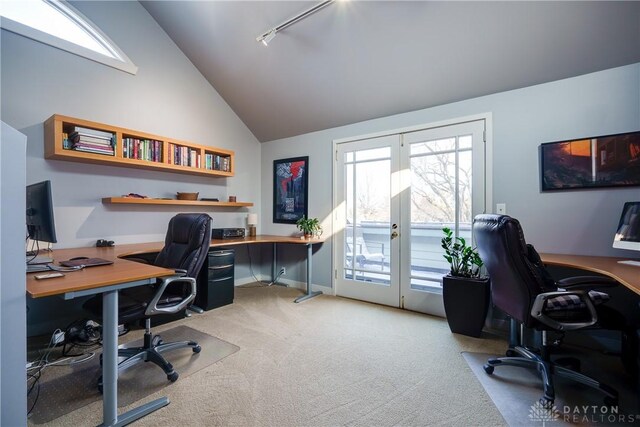 carpeted home office with track lighting, french doors, and vaulted ceiling