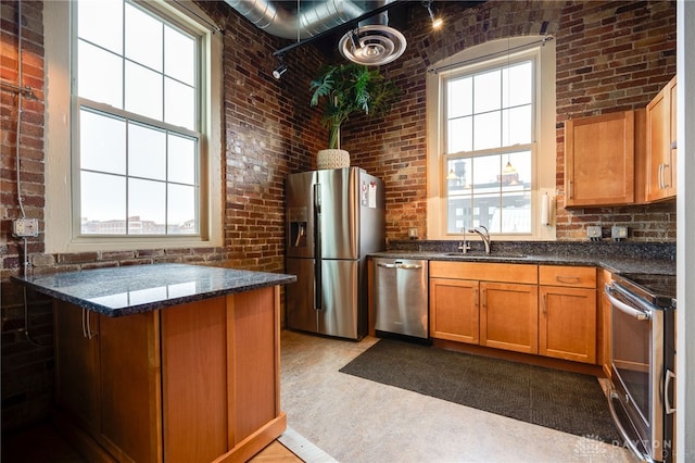 kitchen with brick wall, stainless steel appliances, plenty of natural light, and sink