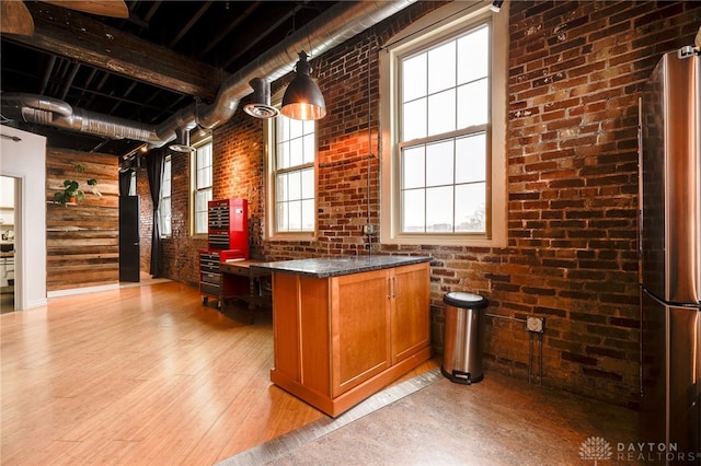 bar with light hardwood / wood-style floors, brick wall, stainless steel fridge, and dark stone counters