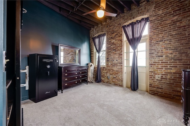 carpeted bedroom featuring ceiling fan, brick wall, and beamed ceiling