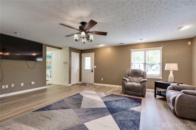 living room featuring a textured ceiling, ceiling fan, and light wood-type flooring