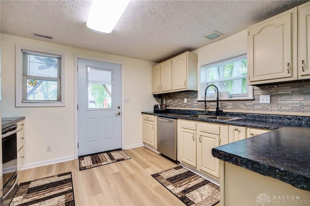 kitchen featuring a textured ceiling, light hardwood / wood-style flooring, decorative backsplash, appliances with stainless steel finishes, and sink