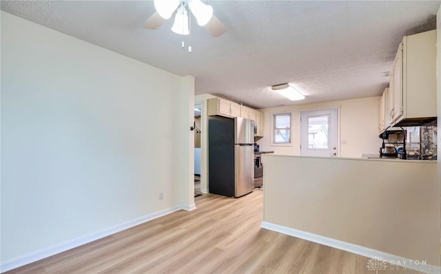 kitchen featuring a textured ceiling, ceiling fan, stainless steel fridge, and light hardwood / wood-style flooring