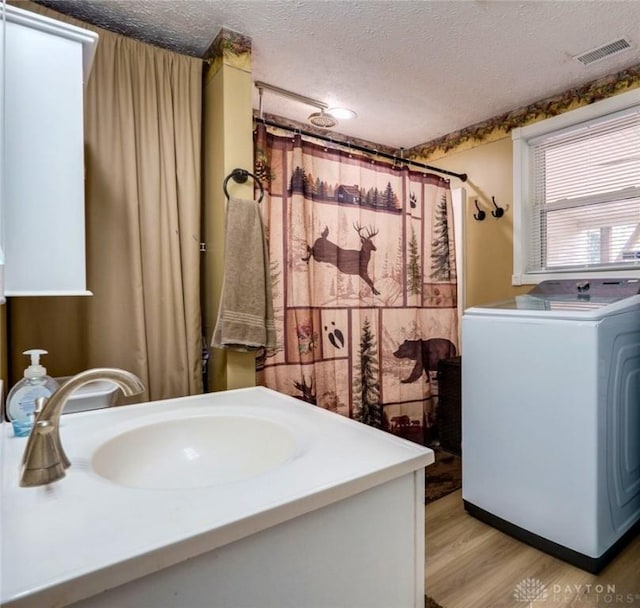 bathroom with a textured ceiling, washer / clothes dryer, vanity, and hardwood / wood-style flooring