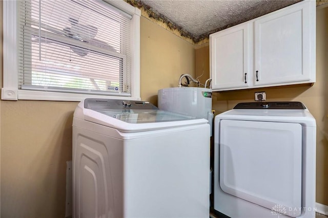 laundry area featuring a textured ceiling, cabinets, gas water heater, and independent washer and dryer