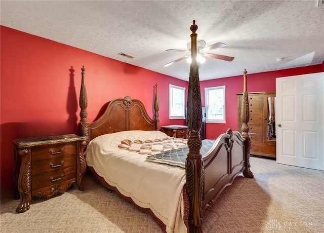 bedroom with a textured ceiling, light colored carpet, and ceiling fan