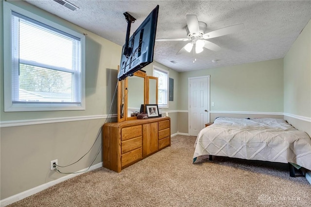 bedroom with multiple windows, a textured ceiling, ceiling fan, and light colored carpet