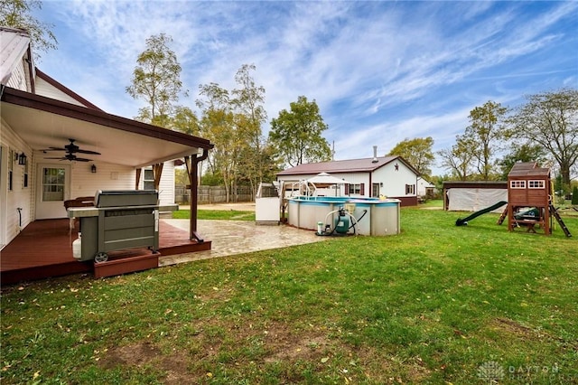 view of yard with ceiling fan, a patio, a playground, and a pool side deck