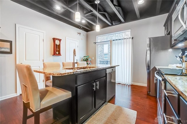 kitchen with stainless steel appliances, sink, pendant lighting, dark hardwood / wood-style floors, and a breakfast bar