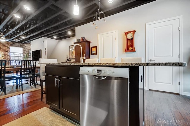 kitchen featuring dark wood-type flooring, stainless steel dishwasher, brick wall, and pendant lighting