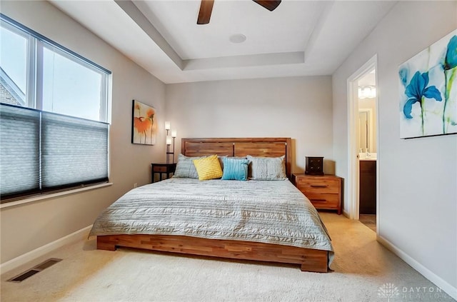 bedroom with ensuite bath, ceiling fan, a tray ceiling, and carpet