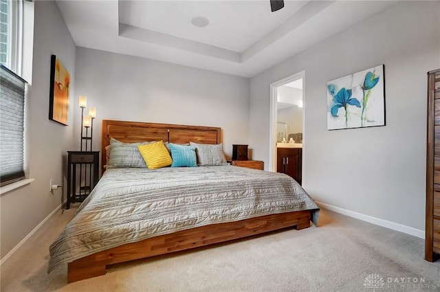 carpeted bedroom featuring ceiling fan, connected bathroom, and a raised ceiling