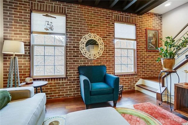 living area with brick wall and dark wood-type flooring