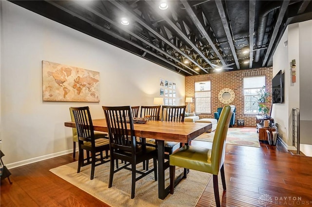 dining room featuring brick wall and dark hardwood / wood-style floors