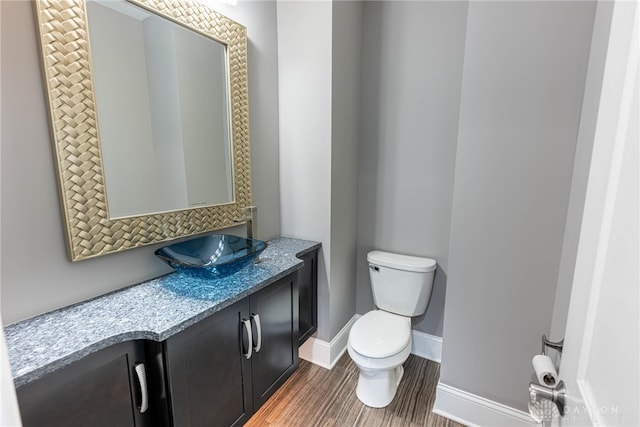 bathroom with toilet, wood-type flooring, and vanity