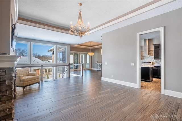 interior space featuring a textured ceiling, an inviting chandelier, a fireplace, and a tray ceiling