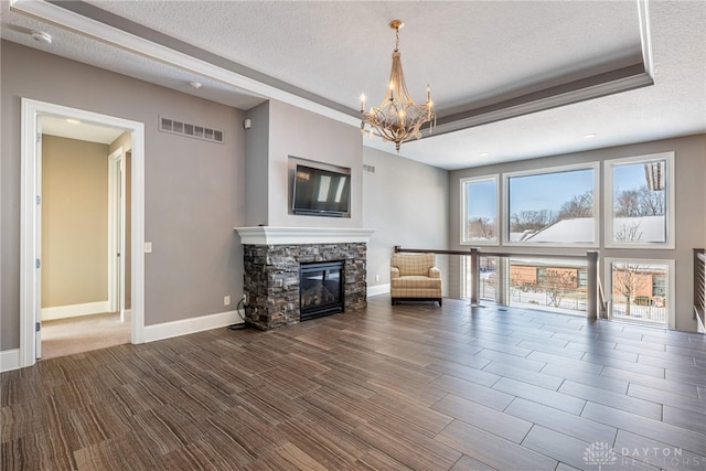 unfurnished living room featuring a textured ceiling, a stone fireplace, and a chandelier