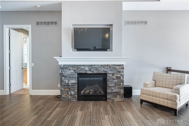 sitting room featuring wood-type flooring and a stone fireplace