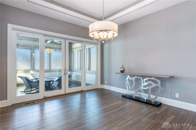 doorway featuring french doors, a chandelier, and a tray ceiling