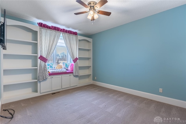 interior space with a textured ceiling, ceiling fan, built in features, and light colored carpet