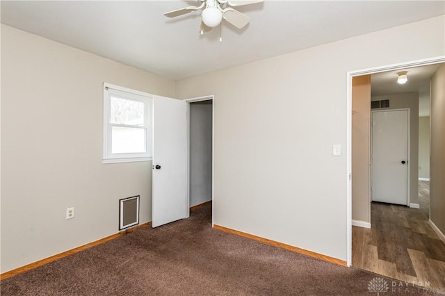 spare room with ceiling fan and dark colored carpet