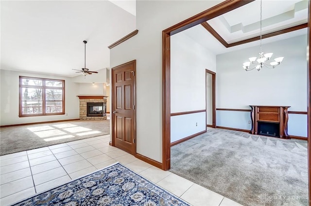 spare room with a towering ceiling, a raised ceiling, ceiling fan with notable chandelier, and light carpet