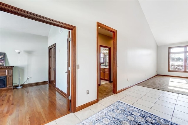 hallway featuring lofted ceiling and light tile patterned floors