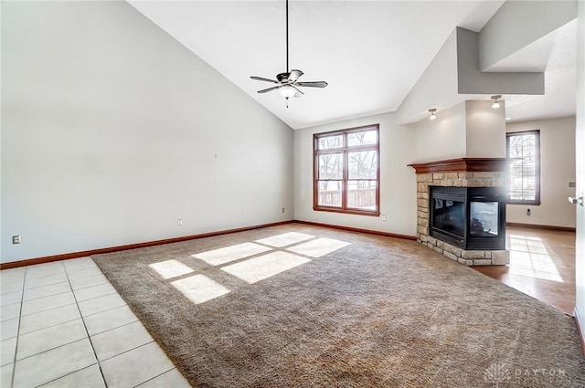 unfurnished living room with light colored carpet, ceiling fan, a stone fireplace, and high vaulted ceiling