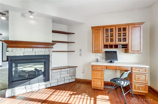 office space with hardwood / wood-style floors, built in desk, and a fireplace