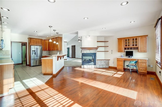 kitchen featuring a kitchen bar, built in desk, hanging light fixtures, stainless steel fridge, and kitchen peninsula