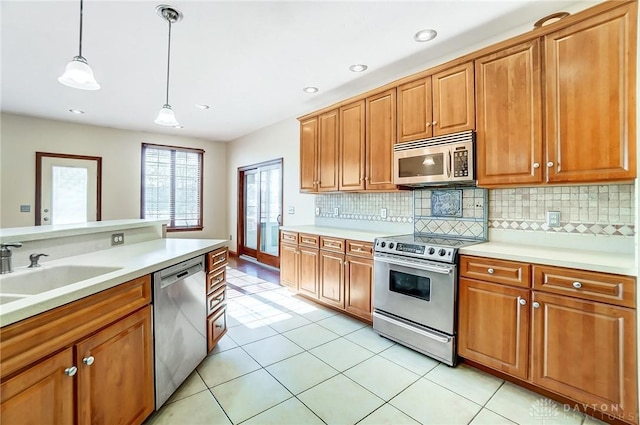 kitchen featuring sink, appliances with stainless steel finishes, hanging light fixtures, backsplash, and light tile patterned flooring