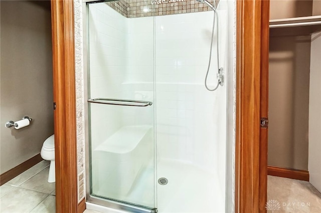 bathroom with tile patterned flooring, a shower with door, and toilet